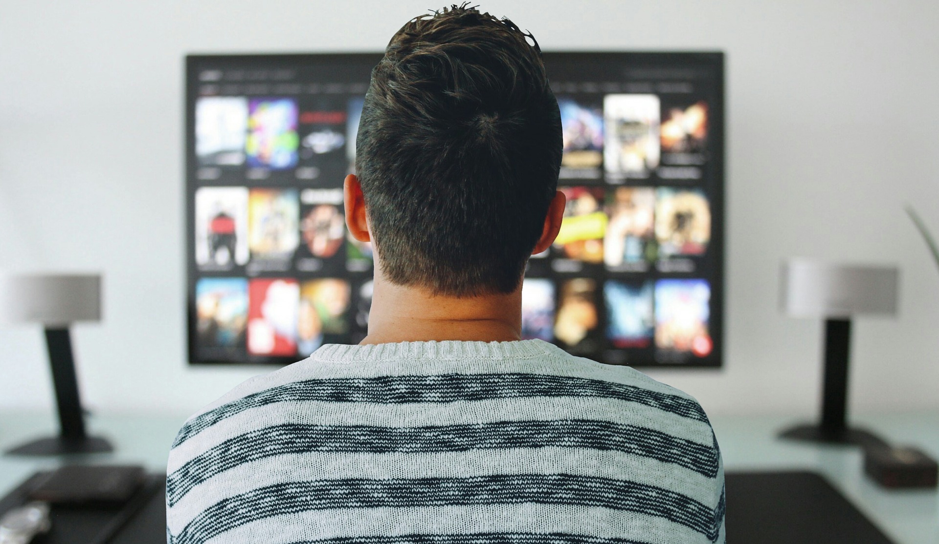 A man with short dark hair staring at a TV screen deciding what to watch
