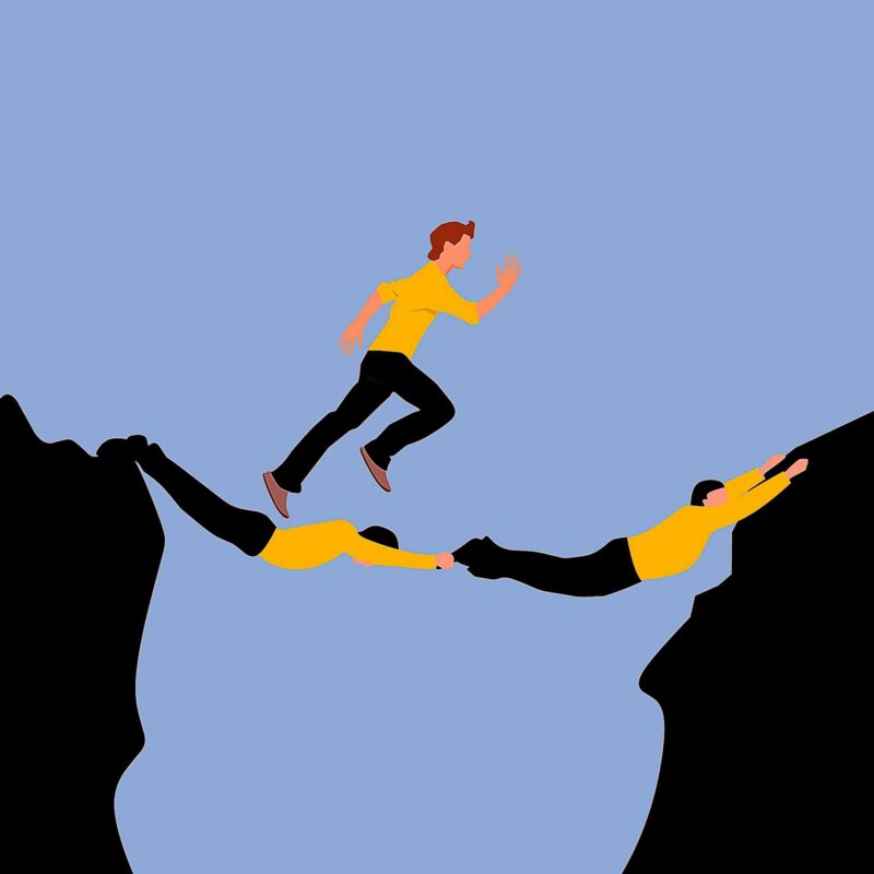 Illustration of a man in a yellow sweater crossing a bridge formed by two men holding opposite cliffs.