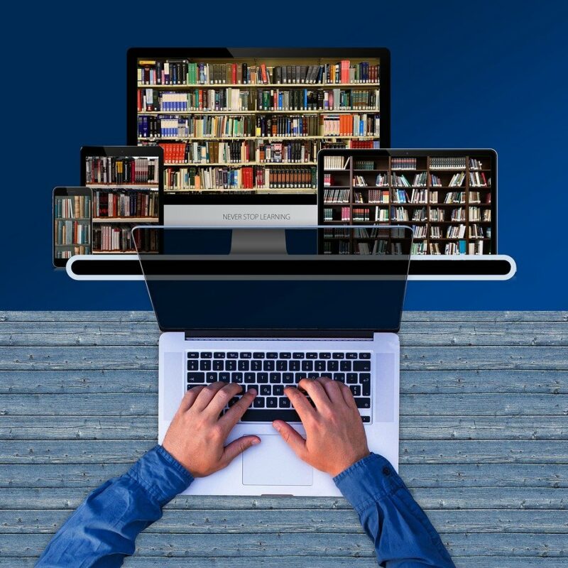 Overhead synthetic image of a person using a laptop, with other laptops arranged above like bookshelves.