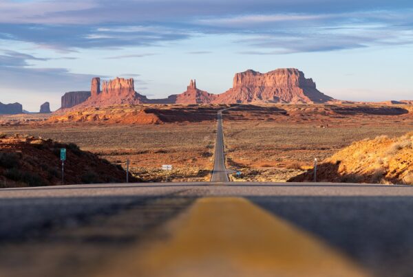 Wide shot of Monument Valley with the highway disappearing into the distance