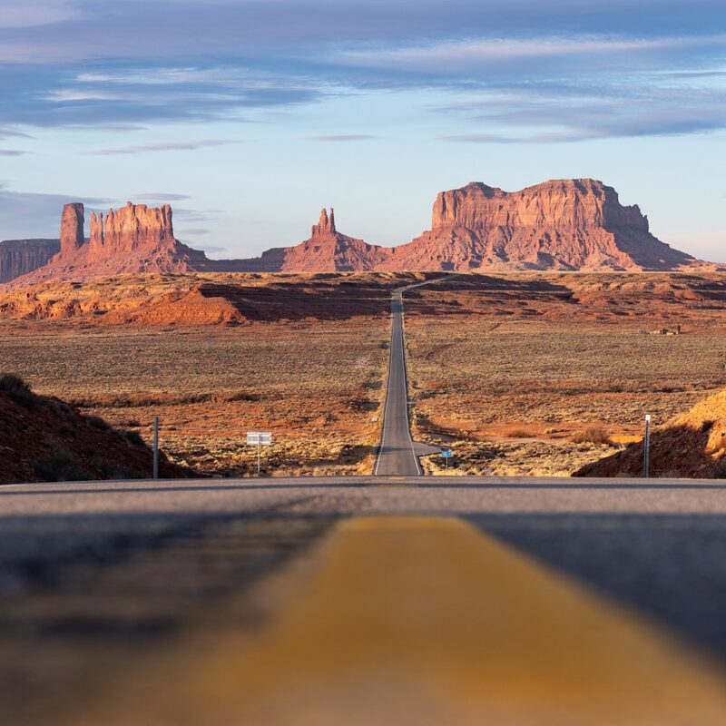 Wide shot of Monument Valley with the highway disappearing into the distance